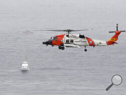 A U.S. Coast Guard helicopter flies over boats searching the area where a boat capsized just off the San Diego coast Sunday, May 2, 2021, in San Diego. (AP Photo/Denis Poroy)