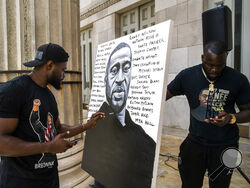 Artist Dennis Owes, 31, from Ghana gives the last touch to his portrait of George Floyd during a rally on Sunday, May 23, 2021, in Brooklyn borough of New York. George Floyd, whose May 25, 2020 death in Minneapolis was captured on video, plead for air as he was pinned under the knee of former officer Derek Chauvin, who was convicted of murder and manslaughter in April 2021. (AP Photo/Eduardo Munoz Alvarez)
