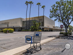 This Thursday, May 27, 2021, photo shows an empty shopping cart in an empty parking lot at the closed Sears in Buena Park Mall in Buena Park, Calif. (AP Photo/Damian Dovarganes)