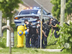 A line of police officers look for evidence at the scene of a car crash in London, Ontario on Monday, June 7, 2021. Police say multiple people have died after several pedestrians were struck by a car Sunday night. (Geoff Robins/The Canadian Press via AP)
