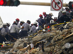 Search and rescue workers carry equipment onto the rubble of an oceanfront condo building that collapsed the week before, with many dead and unaccounted for, in Surfside, Fla., Tuesday, June 29, 2021. (AP Photo/Gerald Herbert)