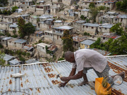 Antony Exilien secures the roof of his house in response to Tropical Storm Elsa, in Port-au-Prince, Haiti, Saturday, July 3, 2021. Elsa brushed past Haiti and the Dominican Republic on Saturday and threatened to unleash flooding and landslides before taking aim at Cuba and Florida. ( AP Photo/Joseph Odelyn)