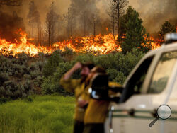 U.S. Forest Service firefighters Chris Voelker, left, and Kyle Jacobson monitor the Sugar Fire, part of the Beckwourth Complex Fire, burning in Plumas National Forest, Calif., on Friday, July 9, 2021. The Beckwourth Complex — a merging of two lightning-caused fires — headed into Saturday showing no sign of slowing its rush northeast from the Sierra Nevada forest region after doubling in size only a few days earlier. (AP Photo/Noah Berger)
