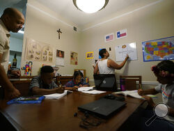 Arlena Brown, center, holds her youngest child, Lucy, 9 months, as she and husband, Robert, left, lead their other children, from left, Jacoby, 11; Felicity, 9, and Riley, 10, through math practice at their home in Austin, Texas, Tuesday, July 13, 2021. “I didn’t want my kids to become a statistic and not meet their full potential,” said Robert, a former teacher who now does consulting. “And we wanted them to have very solid understanding of their faith.” (AP Photo/Eric Gay)