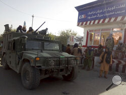 Taliban fighters stand guard at a checkpoint in Kunduz city, northern Afghanistan, Monday, Aug. 9, 2021. The militants have ramped up their push across much of Afghanistan in recent weeks, turning their guns on provincial capitals after taking district after district and large swaths of land in the mostly rural countryside. (AP Photo/Abdullah Sahil)