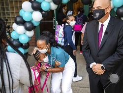 Principal Andrea Harper hugs a student as Harper and Superintendent Kent P. Scribner greet students on the first day of school Monday, Aug. 16, 2021, at T.A. Sims Elementary School in Fort Worth, Texas. (Yffy Yossifor/Star-Telegram via AP)