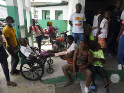 People injured in a car accident, sitting right, wait with others injured during the earthquake for x-rays at the General Hospital in Les Cayes, Haiti, Wednesday, Aug. 18, 2021. (AP Photo/Fernando Llano)