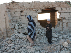 Afghan boys walk near a damaged house after airstrikes in two weeks ago during a fight between government forces and the Taliban in Lashkar Gah, Helmand province, southwestern, Afghanistan, Saturday, Aug. 21, 2021. (AP Photo/Abdul Khaliq)