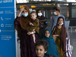 Families evacuated from Kabul, Afghanistan, walk through the terminal before boarding a bus after they arrived at Washington Dulles International Airport, in Chantilly, Va., on Friday, Aug. 27, 2021. (AP Photo/Jose Luis Magana)