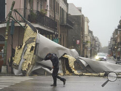 A man passes by a section of roof that was blown off of a building in the French Quarter by Hurricane Ida winds, Sunday, Aug. 29, 2021, in New Orleans. (AP Photo/Eric Gay)