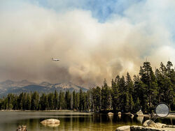 A tanker flies over Wrights Lake while battling the Caldor Fire in Eldorado National Forest, Calif., on Wednesday, Sept. 1, 2021. (AP Photo/Noah Berger)