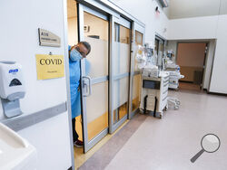 FILE - In this July 16, 2021, file photo, a nurse sticks her head out of a room of a COVID-19 patient in the CoxHealth Emergency Department in Springfield, Mo. The COVID-19 pandemic has created a nurse staffing crisis that is forcing many U.S. hospitals to pay top dollar to get the help they need to handle the crush of patients this summer. (Nathan Papes/The Springfield News-Leader via AP)