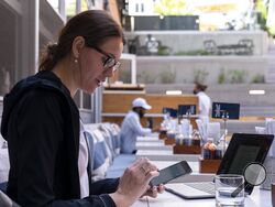 Baylee Bowers pays for her lunch using her cell phone at Bartaco in Arlington, Va., on Thursday, Sept. 2, 2021. The restaurant is using an automated app for ordering and payments. Instead of servers they use "food runners" to get orders to tables. "I like it," says Bowers of the automation, "it was easy. I'm a flight attendant so as long as automation doesn't come for my job I'm ok with it." (AP Photo/Jacquelyn Martin)