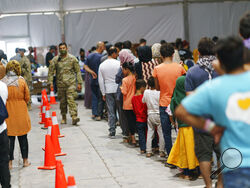 Afghan refugees line up for food in a dining hall at Fort Bliss' Doña Ana Village, in New Mexico, where they are being housed, Friday, Sept. 10, 2021. The Biden administration provided the first public look inside the U.S. military base where Afghans airlifted out of Afghanistan are screened, amid questions about how the government is caring for the refugees and vetting them. (AP Photo/David Goldman)
