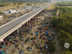 Migrants, many from Haiti, are seen at an encampment along the Del Rio International Bridge near the Rio Grande, Tuesday, Sept. 21, 2021, in Del Rio, Texas. The options remaining for thousands of Haitian migrants straddling the Mexico-Texas border are narrowing as the United States government ramps up to an expected six expulsion flights to Haiti and Mexico began busing some away from the border. (AP Photo/Julio Cortez)