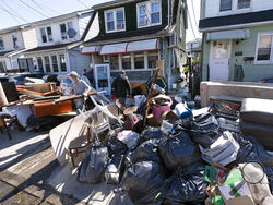 FILE - In this Sept. 3, 2021 file photo, people clear debris and damaged belongings from their homes in the Queens borough of New York. Floodwaters from the remnants of Hurricane Ida have long receded but Northeast residents still in the throes of recovery are being hit with another unexpected blow: Thousands of families without flood insurance are now swamped with financial losses after runoff from the fierce storm submerged basements, cracked foundations and destroyed valuable belongings. (AP Photo/Mark L