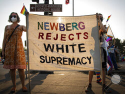 Cherice Boch, left, and her son Espen take part in a protest on Aug. 24 2021, in Newberg, Ore., against a new school policy that bans Black Lives Matter and Pride flags across Newberg School District facilities. The policy has prompted a torrent of recriminations and threats to boycott the town and its businesses. (Jozie Donaghey/The Oregonian via AP)