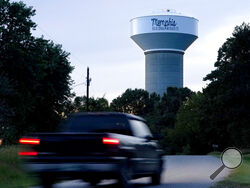 A truck drives down a rural road near a water tower marking the location of the Memphis Regional Megasite on Sept. 24, 2021, in Stanton, Tenn. Ford Motor Co. and SK Innovation of South Korea plan to build three new electric-vehicle battery factories and an auto assembly plant by 2025 in Tennessee and Kentucky. The industrial site in Stanton will be the location for a factory to produce electric F-Series pickups and a battery factory. (AP Photo/Mark Humphrey)