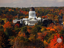 FILE - In this Oct. 23, 2017, file photo, the State House is surrounded by fall foliage in Augusta, Maine. Recent leaf-peeping seasons have been disrupted by weather conditions in New England, New York and elsewhere. Arborists and ecologists say the trend is likely to continue as the planet warms. (AP Photo/Robert F. Bukaty, File)