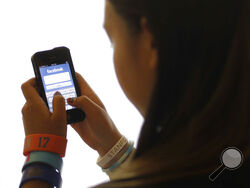 FILE - In this June 4, 2012, file photo, an unidentified 11-year-old girl logs into Facebook on her iPhone at her home in Palo Alto, Calif. Facebook, in the aftermath of damning testimony that its platforms harm children, will be introducing several features including prompting teens to take a break using its photo sharing app Instagram, and “nudging" teens if they are repeatedly looking at the same content that's not conducive to their well-being. (AP Photo/Paul Sakuma, File)