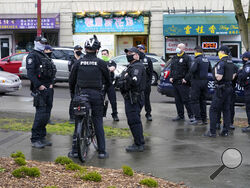 FILE - Seattle Police officers confer after taking part in a public roll call at Hing Hay Park in Seattle's Chinatown-International District Thursday, March 18, 2021. Seattle's police department is having detectives and non-patrol staff respond to emergency calls because of a shortage of officers union leaders fear will be made worse by COVID-19 vaccine mandates. (AP Photo/Ted S. Warren, File)