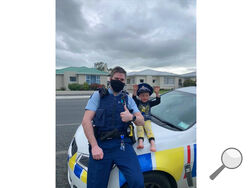 In this photo released by New Zealand Police, an officer identified only as Constable Kurt sits on his patrol car with a 4-year-old boy who is not identified, in the South Island city of Invercargill, New Zealand, Friday, Oct. 15, 2021. An emergency call made by the 4-year-old New Zealand boy asking for police to come over and check out his toys prompted a real-life callout and confirmation from an officer that the toys were, indeed, pretty cool. (NZ Police via AP)