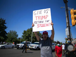 FILE - A resident holds a placard and shouts slogans against President Joe Biden as people wait for his motorcade in the streets of Manville, N.J., Sept. 7, 2021. (AP Photo/Eduardo Munoz Alvarez)