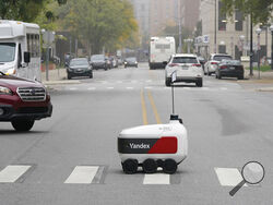 A food delivery robot crosses a street in Ann Arbor, Mich. on Thursday, Oct. 7, 2021. Robot food delivery is no longer the stuff of science fiction. Hundreds of little robots __ knee-high and able to hold around four large pizzas __ are now navigating college campuses and even some city sidewalks in the U.S., the U.K. and elsewhere. While robots were being tested in limited numbers before the coronavirus hit, the companies building them say pandemic-related labor shortages and a growing preference for conta