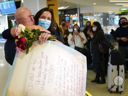 People applaud and take pictures as MaKensi Kastl greets her boyfriend, Thierry Coudassot, after he arrived from France at Newark Liberty International Airport in Newark, N.J., Monday, Nov. 8, 2021. The couple has not seen one another in person for over a year due to pandemic travel restrictions. The U.S. lifted restrictions Monday on travel from a long list of countries including Mexico, Canada and most of Europe, setting the stage for emotional reunions nearly two years in the making and providing a boost