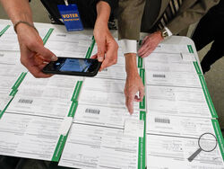 FILE - A canvas observer photographs Lehigh County provisional ballots as vote counting in the general election continues, Nov. 6, 2020, in Allentown, Pa. A review by The Associated Press in the six battleground states disputed by former President Trump has found fewer than 475 cases of potential voter fraud, a minuscule number that would have made no difference in the 2020 presidential election. Democrat Joe Biden won Arizona, Georgia, Michigan, Nevada, Pennsylvania and Wisconsin and their 79 Electoral Col