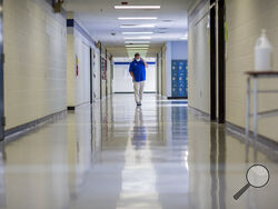FILE - A middle school principal walks the empty halls of his school as he speaks with one of his teachers to get an update on her COVID-19 symptoms, Friday, Aug., 20, 2021, in Wrightsville, Ga. On Monday, Dec. 27, 2021, U.S. health officials cut isolation restrictions for Americans who catch the coronavirus from 10 to five days, and also shortened the time that close contacts need to quarantine. (AP Photo/Stephen B. Morton, File)