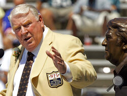 FILE - Former Oakland Raiders coach John Madden gestures toward a bust of himself during his enshrinement into the Pro Football Hall of Fame in Canton, Ohio, Aug. 5, 2006. John Madden, the Hall of Fame coach turned broadcaster whose exuberant calls combined with simple explanations provided a weekly soundtrack to NFL games for three decades, died Tuesday, Dec. 28, 2021, the NFL said. He was 85. (AP Photo/Mark Duncan, File)