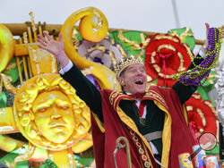 FILE - Actor Bryan Cranston waves beads as he acts as the celebrity monarch of the Krewe of Orpheus along the Uptown parade route during Mardi Gras celebrations in New Orleans, on Feb. 24, 2020. Vaccinated, masked and ready-to-revel New Orleans residents will usher in Carnival season Thursday with a rolling party on the city's historic streetcar line, an annual march honoring Joan of Arc in the French Quarter and a collective, wary eye on coronavirus statistics. (AP Photo/Matthew Hinton, File)