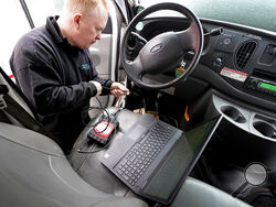 Brian Hohmann, mechanic and owner of Accurate Automotive, in Burlington, Mass., attaches a diagnostics scan tool, center left, to a vehicle and a laptop computer, below, Tuesday, Feb. 1, 2022, in Burlington. The diagnostics scan tool sends information from the vehicle's computer to the laptop so a mechanic can view information about the vehicle's performance. Hohmann said most independent shops are perfectly capable of competing with dealerships on both repair skills and price as long as they have the infor