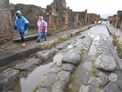 Tourists walk inside the Pompeii archaeological site in southern Italy, Tuesday, Feb. 15, 2022. In a few horrible hours, Pompeii went from being a vibrant city to a dead one, smothered by a furious volcanic eruption in 79 AD. Then in this century, Pompeii appeared alarmingly on the precipice of a second death, assailed by decades of neglect, mismanagement and scanty systematic maintenance of heavily visited ruins. (AP Photo/Gregorio Borgia)
