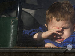 A boy waiting to be evacuated to Russia looks through the window of a bus, in Donetsk, the territory controlled by pro-Russian militants, eastern Ukraine, Saturday, Feb. 19, 2022. On Friday, separatist authorities in eastern Ukraine announced a mass evacuation of women, children and older adults to neighboring Russia. The moves have have fueled Western fears that Moscow could use the latest violence in eastern Ukraine as a pretext for an invasion. (AP Photo/Alexei Alexandrov)