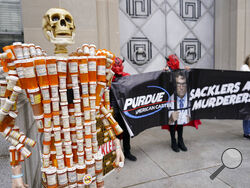 FILE - Pill Mann" made by Frank Huntley of Worcester, Mass., from his opioid prescription pill bottles, is displayed during a protest by advocates for opioid victims outside the Department of Justice, on Dec. 3, 2021, in Washington. Many families left heartbroken by opioid overdoses and addictions have been waiting for years to be able to tell another family – the Sacklers – about the damage their company, Purdue Pharma, did. Their chance arrives Thursday, March 10, 2022, in a federal court hearing to be co