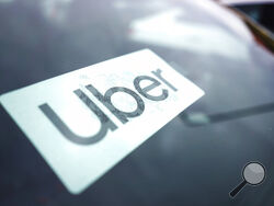 FILE - An Uber sign is displayed inside a car in Palatine, Ill., Thursday, Feb. 10, 2022. Citing record-high prices for gasoline, Uber is charging customers a new fuel fee to help offset costs for ride-hail and delivery drivers. The company announced Friday, March 11, 2022, that the temporary surcharge will be either 45 cents or 55 cents for each Uber trip and either 35 cents or 45 cents for each Uber Eats order, depending on location. (AP Photo/Nam Y. Huh, File)