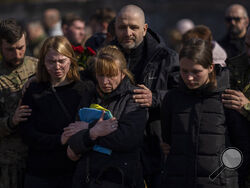 Relatives and friends attend the funeral of Ukrainian Colonel Oleg Yaschyshyn in Lviv, Ukraine, Tuesday, March 15, 2022. Yaschyshyn was killed during Sunday's Russian missile strike on a military training base near Ukraine's western border with NATO member Poland. (AP Photo/Bernat Armangue)