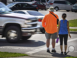 FILE - In this June 8, 2016, file photo, a maroon and silver truck drove, left, drives through the marked crosswalk in front of pedestrian volunteers Dave Passiuk and Nelsie Yang in St. Paul, Minn. Drivers of bigger vehicles such as pickup trucks and SUVs are more likely to hit pedestrians while making turns than drivers of cars, according to a new study. The research released Thursday, March 17, 2022, by the Insurance Institute for Highway Safety points to the increasing popularity of larger vehicles as a 