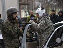 A wounded man talks to a soldier, left, after being evacuated from Irpin, on the outskirts of Kyiv, Ukraine, Wednesday, March 30, 2022. (AP Photo/Rodrigo Abd)