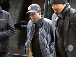 Chris Rock, center, arrives at the Wilbur Theater before a performance, Wednesday, March 30, 2022, in Boston. (AP Photo/Michael Dwyer)