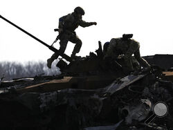 A Ukrainian serviceman walks on a destroyed Russian fighting vehicle in Bucha, Ukraine, Thursday, April 7, 2022. Russian troops left behind crushed buildings, streets littered with destroyed cars and residents in dire need of food and other aid in a northern Ukrainian city, giving fuel to Kyiv's calls Thursday for more Western support to help halt Moscow's offensive before it refocuses on the country's east. (AP Photo/Vadim Ghirda)