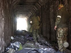 FILE - Servicemen of the Donetsk People's Republic militia look at bodies of Ukrainian soldiers placed in plastic bags in a tunnel, part of the Illich Iron & Steel Works Metallurgical Plant, the second largest metallurgical enterprise in Ukraine, in an area controlled by Russian-backed separatist forces in Mariupol, Ukraine, Monday, April 18, 2022. On Thursday, April 21, 2022, Russian President Vladimir Putin ordered his forces not to storm the last remaining Ukrainian stronghold in the besieged city of Mar