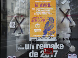 FILE - A torn front page ad shows incubent President Emmanuel Macron and challenger Marine Le Pen as the environmental group Extinction Rebellion takes part in a three-day demonstration against what they call France's inaction on climate issues, in the district of Porte de Saint Denis in the center of Paris, France, Monday, April 18, 2022. French President Emmanuel Macron is in pole position to win reelection Sunday, April 24, 2022 in France's presidential runoff. Yet his lead over far-right rival Marine Le