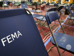 FILE - A portable cot, with the Federal Emergency Management Agency logo FEMA printed on the backrest, and other cots line the basketball court at a makeshift medical facility in a gymnasium at Southern New Hampshire University in Manchester, N.H., March 24, 2020. FEMA may have been double-billed for the funerals of hundreds of people who died of COVID-19, the Government Accountability Office said in a new report Wednesday, April 27, 2022. (AP Photo/Charles Krupa, File)