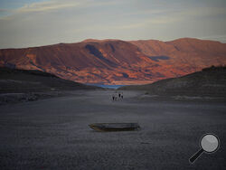 A formally sunken boat sits on cracked earth hundreds of feet from what is now the shoreline on Lake Mead at the Lake Mead National Recreation Area, Monday, May 9, 2022, near Boulder City, Nev. Lake Mead is receding and Sin City is awash with mob lore after a second set of human remains emerged within a week from the depths of the drought-stricken Colorado River reservoir just a short drive from the Las Vegas Strip. (AP Photo/John Locher)