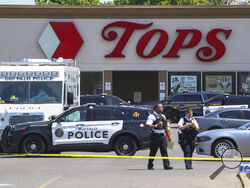Police walk outside the Tops grocery store on Sunday, May 15, 2022, in Buffalo, N.Y. A white 18-year-old wearing military gear and livestreaming with a helmet camera opened fire with a rifle at the supermarket, killing and wounding people in what authorities described as “racially motivated violent extremism.” (AP Photo/Joshua Bessex)