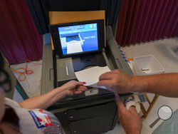Polling judge Frank Kosek, right, Elaine Rhone, left, guide her ballot into a voting machine during the Pennsylvania primary election, at Mont Alto United Methodist Church in Alto, Pa., Tuesday, May 17, 2022. (AP Photo/ Carolyn Kaster)
