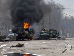 FILE - A Russian armored personnel carrier burns amid damaged and abandoned light utility vehicles after fighting in Kharkiv, the country's second-largest city in Ukraine, Feb. 27, 2022. Three months after it invaded Ukraine hoping to overtake the country in a blitz, Russia has bogged down in what increasingly looks like a war of attrition with no end in sight. (AP Photo/Marienko Andrew, File)